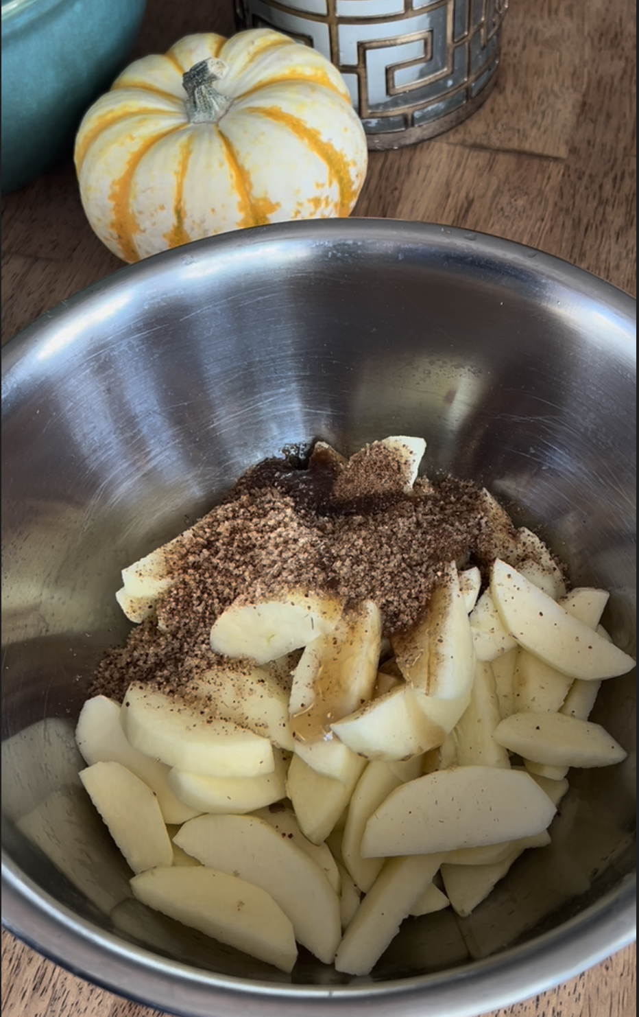 "Ingredients for apple galette including apple slices, brown sugar, coconut sugar, and vanilla extract arranged on a countertop."